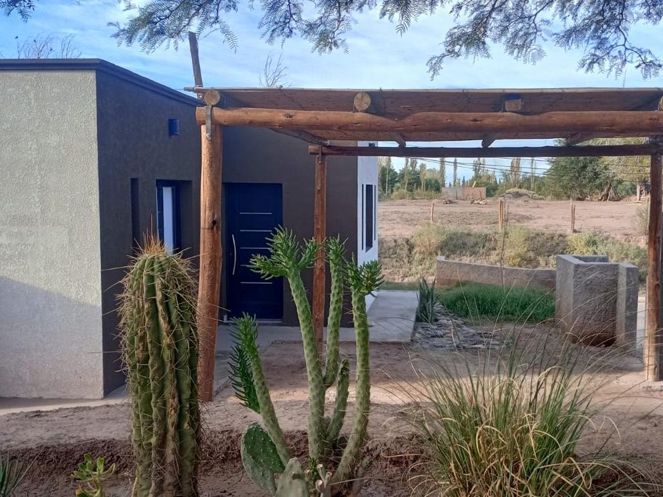 El frente de la Casa 2, con la galería de troncos y los cactus